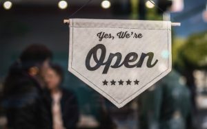 Sign on front door of small business that says "Yes, we're open"