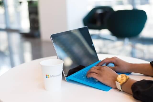 Man using Windows Surface with a cup of coffee on the table showing the Microsoft logo