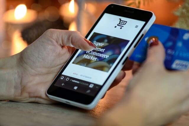 Person holding credit card and smartphone while shopping on an e-commerce website