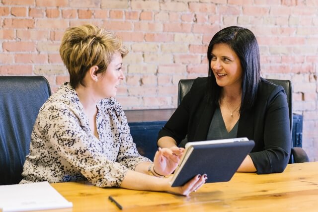 Two woman looking at tablet and discussing the website design process