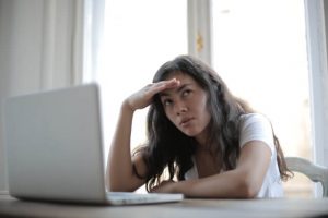 Woman sitting in front of laptop with her head resting on her hand