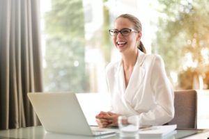 Woman smiling, sitting at desk in front of laptop