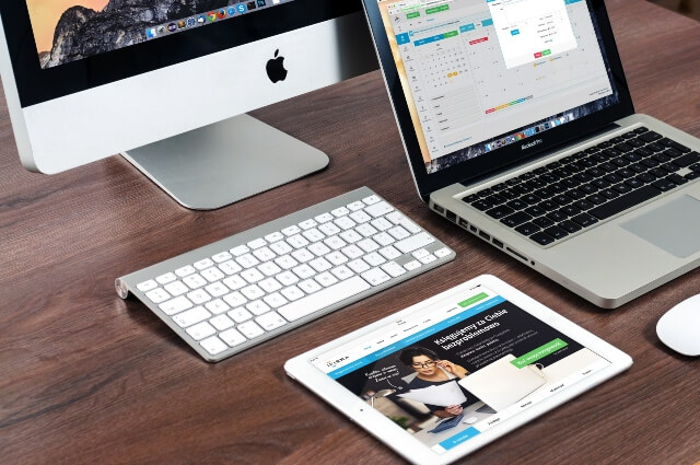 Desktop computer, laptop computer, and tablet sitting on a desk