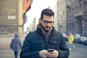 Man standing on street corner checking his mobile device