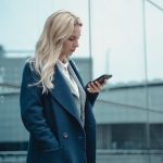 Woman standing outside looking confused while reading a text message