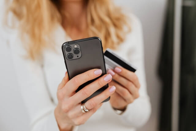 Closeup of woman holding a phone in her right hand and a credit card in her left hand