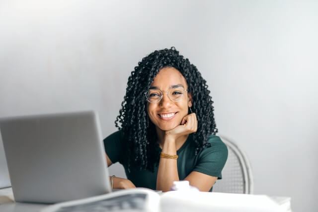 Smiling woman sitting in front of a laptop computer.