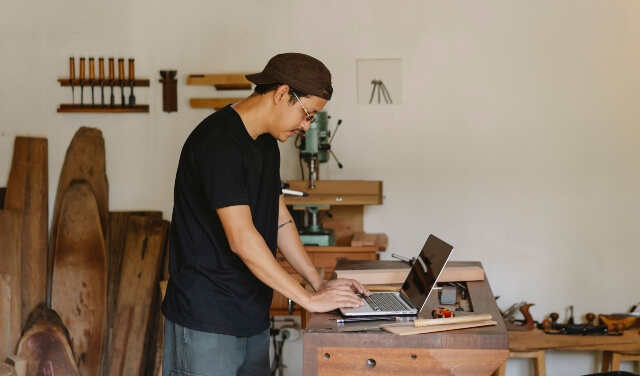 Small Business Owner in woodworking shop updating his Google Business Profile on his laptop