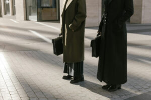 Man and woman in business coats, standing on the sidewalk, holding briefcases