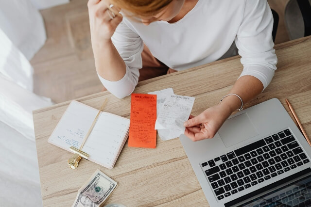 Woman sitting at a computer looking at receipts