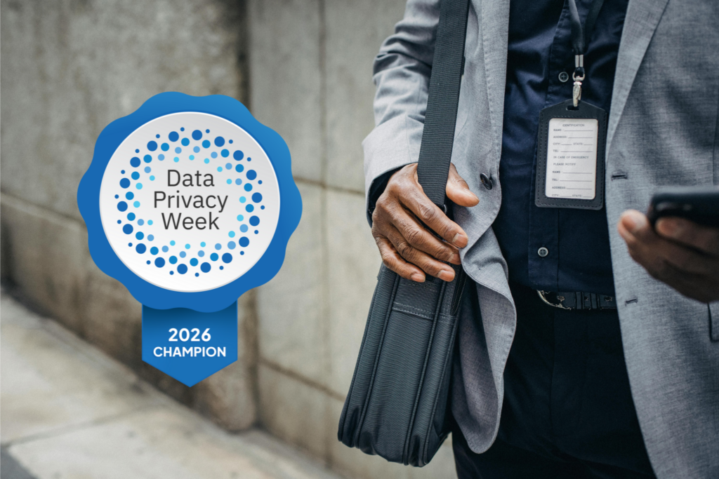 Close-up of man in a suite, holding a laptop bag and looking at his phone. A digital badge to the side of the man reads, "Data Privacy Week, 2026 Champion"
