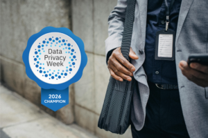 Close-up of man in a suite, holding a laptop bag and looking at his phone. A digital badge to the side of the man reads, "Data Privacy Week, 2026 Champion"
