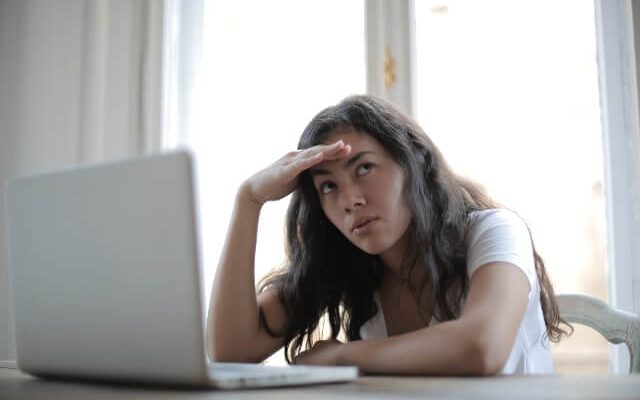 Woman sitting in front of laptop with her head resting on her hand