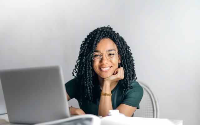 Smiling woman sitting in front of a laptop computer.