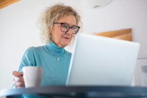 Woman drinking coffee and browsing the internet on a laptop using data security and privacy best practices