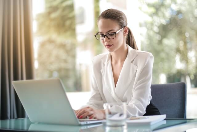 Business woman sitting at desk working on a laptop computer.