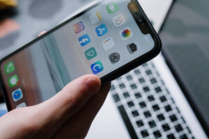 Hand holding a smartphone with a variety of mobile apps
