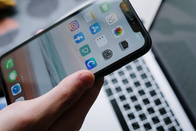 Hand holding a smartphone with a variety of mobile apps