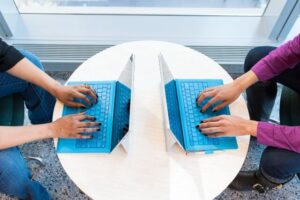 Overhead view of two women sitting across from each other working on separate Microsoft Surface devices