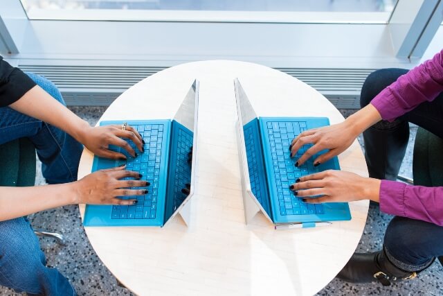 Overhead view of two women sitting across from each other working on separate Microsoft Surface devices