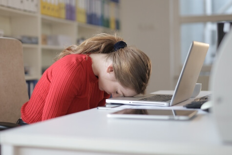 Woman laying her head on the keyboard of a slow laptop