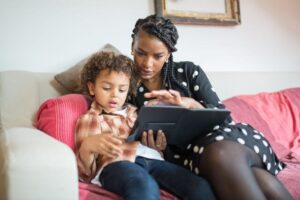 A mother and her son sitting on the couch, reviewing parental controls on a tablet device