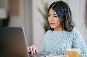 Woman sitting at desk, working on a laptop computer.